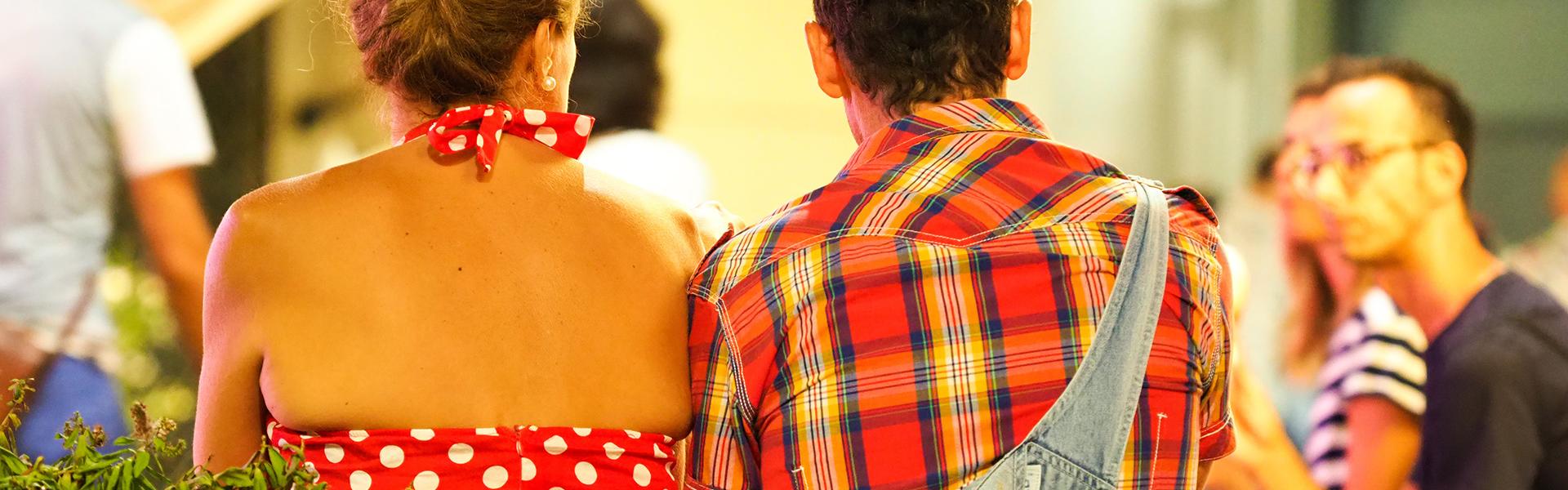 Due persone sedute, una in abito a pois, l'altra in camicia a quadri.